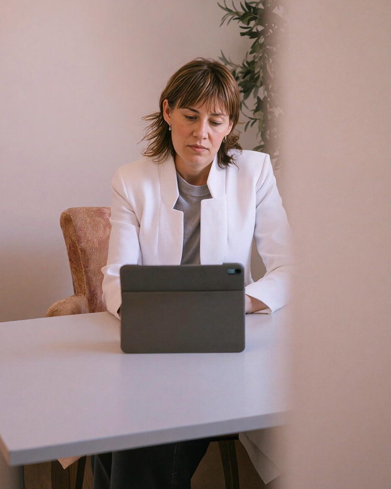 Montse Carreras en su mesa de trabajo, consultando una tableta durante una visita en línea.